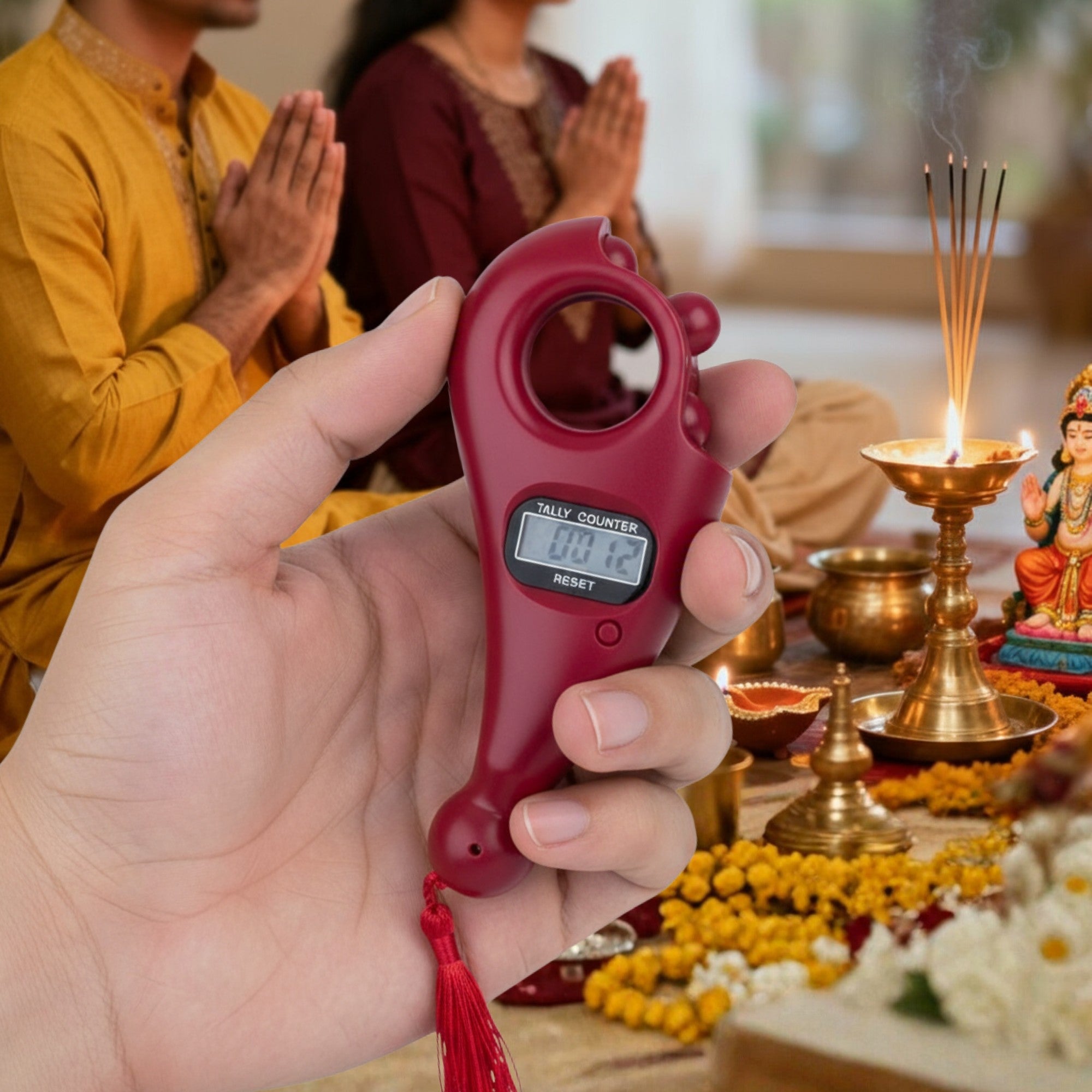 Hand holding a red digital counter with people praying in the background