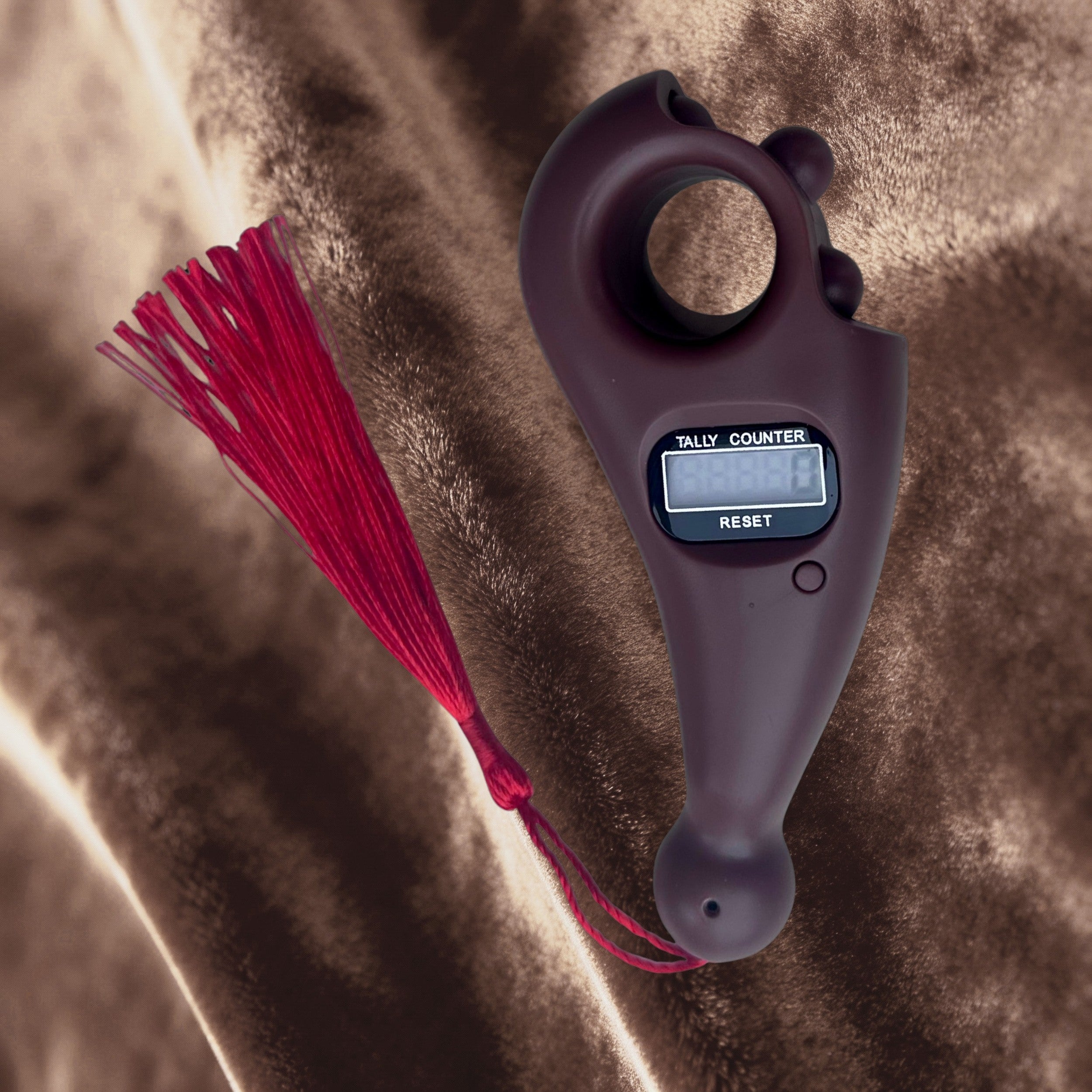 Digital tally counter with a red tassel on a textured surface