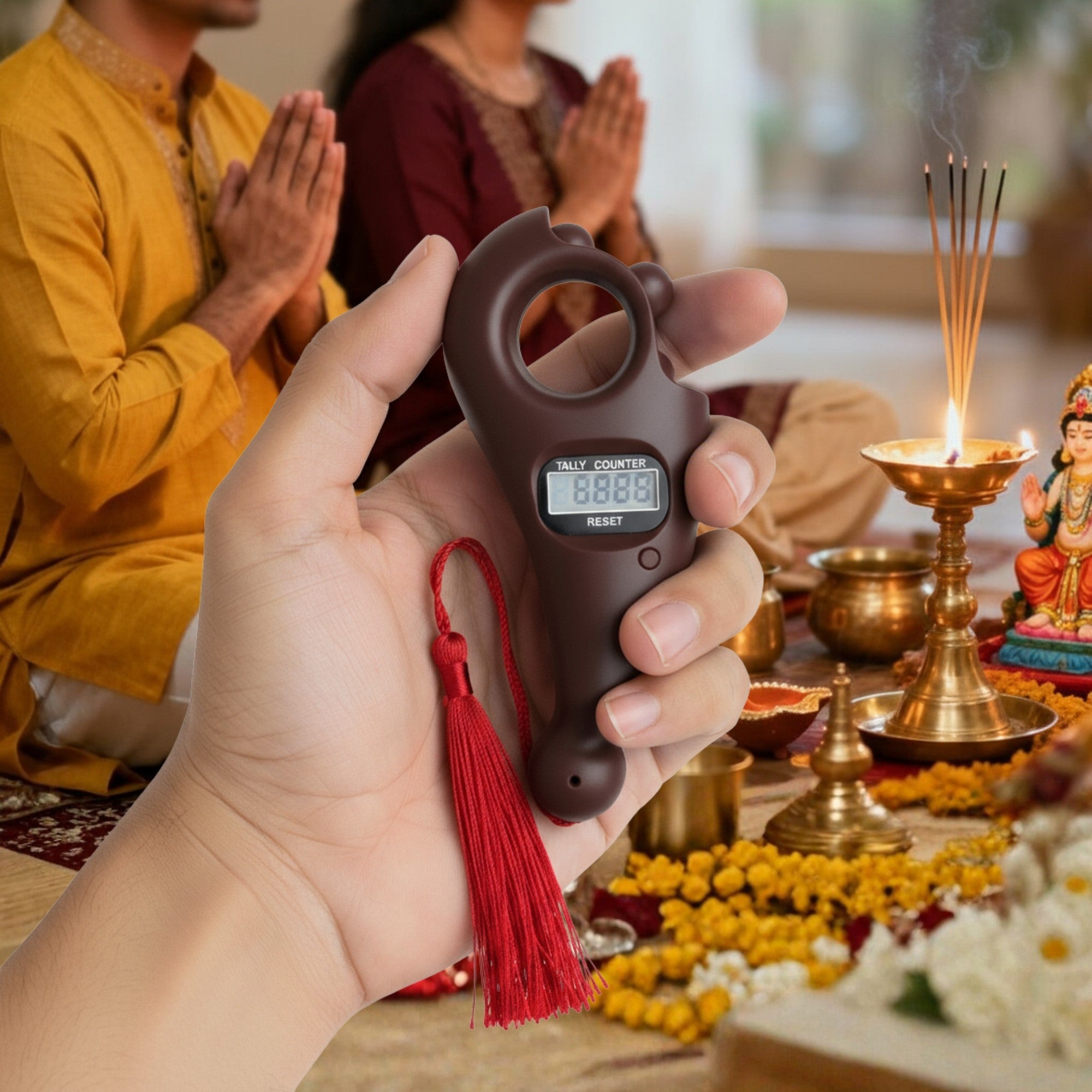 Hand holding a digital counter with tassel in front of a religious ceremony setup.