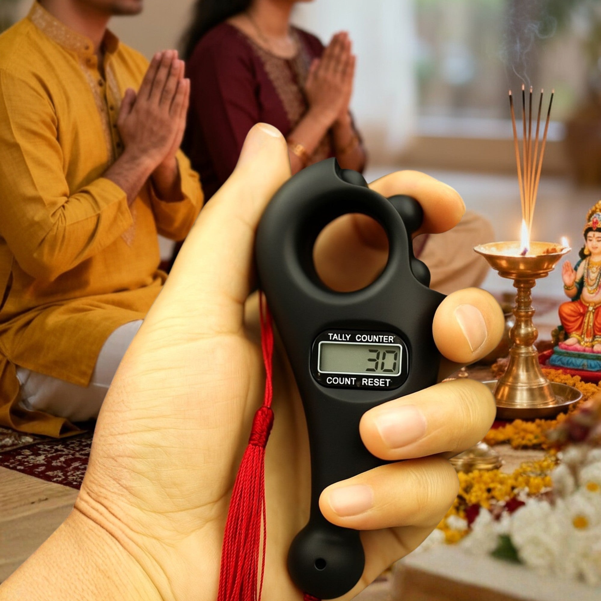 Digital prayer counter held by a hand with people praying in the background