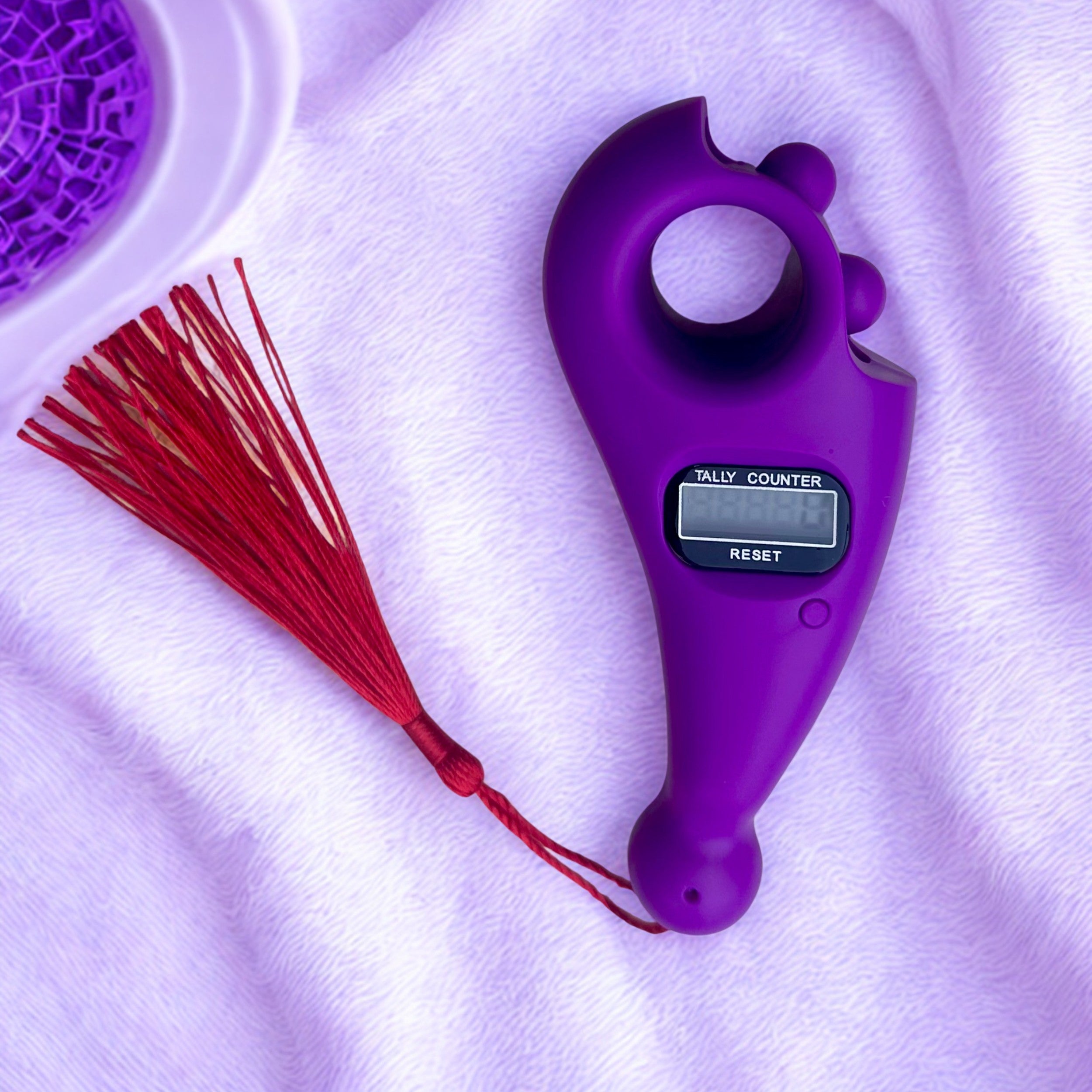 Purple tally counter with a red tassel on a white background