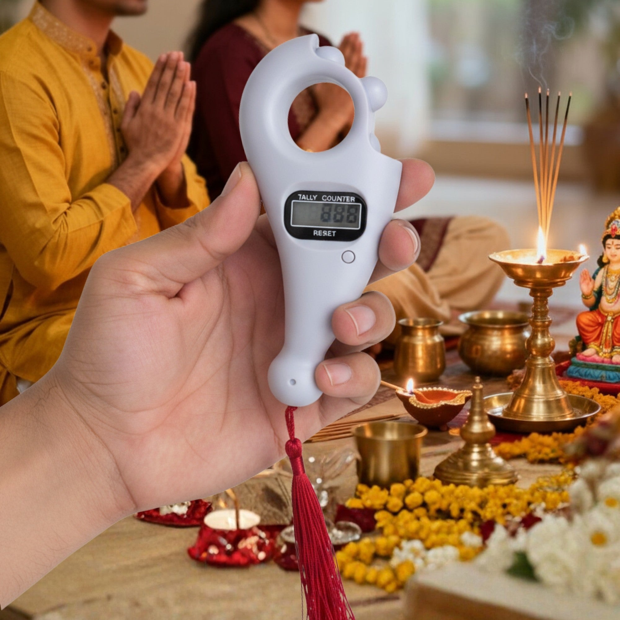 Digital tally counter held by a hand with people and religious items in the background